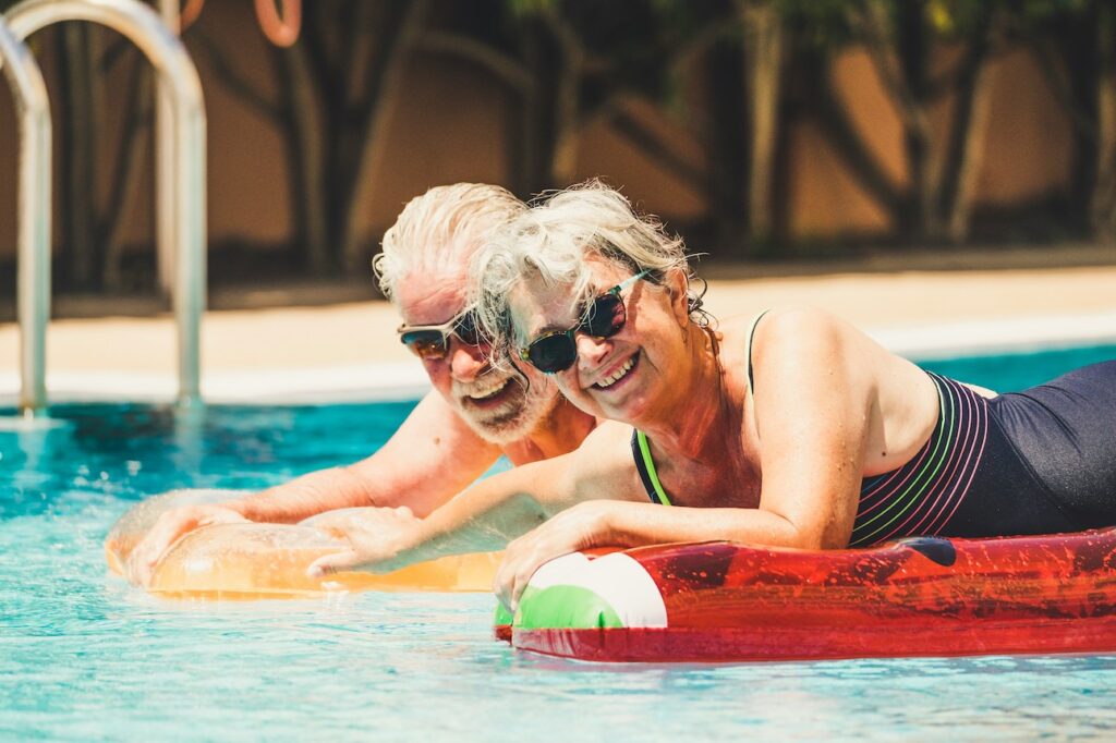 Two mature adults in Florida enjoying their time at the pool in swimsuits floating on inflatables after losing weight with Semaglutide in Sarasota