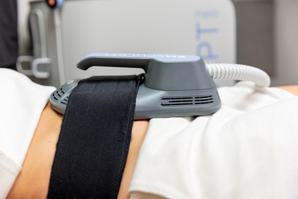 A close-up of a patient receiving Emsculpt NEO near Longboat Key. The largest applicator rests on her abdomen, where it tightens muscles and burns fat.